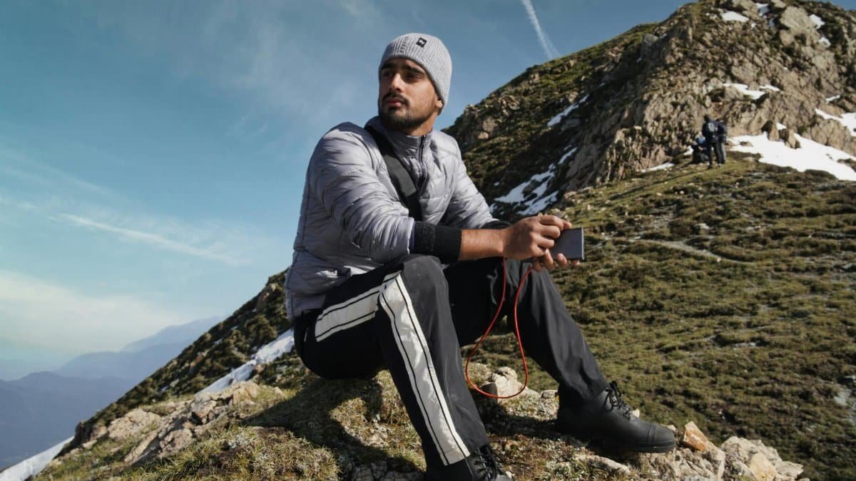 A man sits on a mountain slope in Kashmir, enjoying the scenic view and fresh air.
