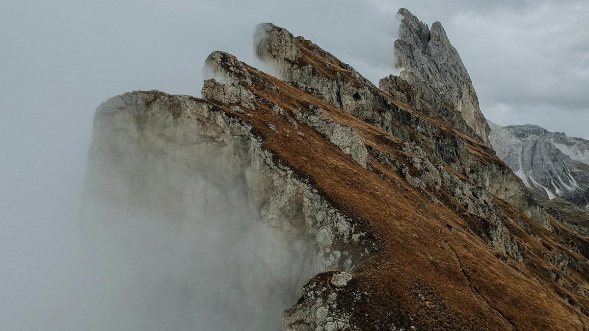 Dramatic foggy landscape of the Seceda mountain peaks in the Dolomites, Italy, during autumn.