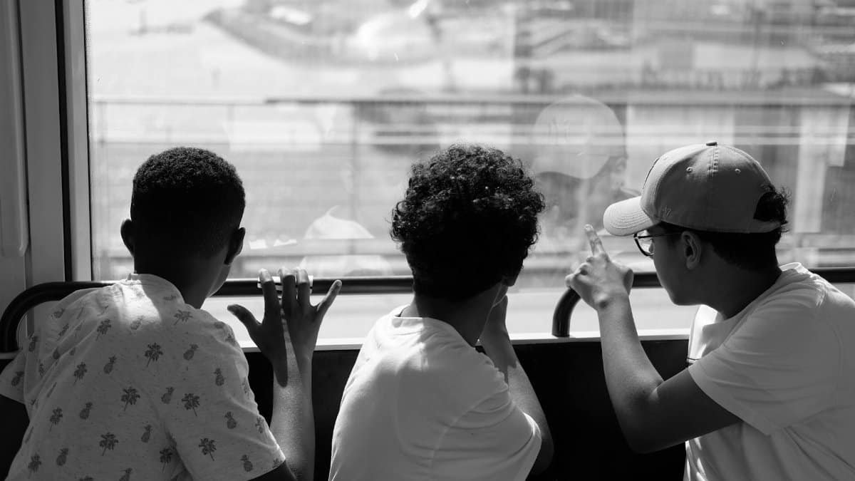 A black and white photo of three boys looking out a window in Rabat, Morocco.