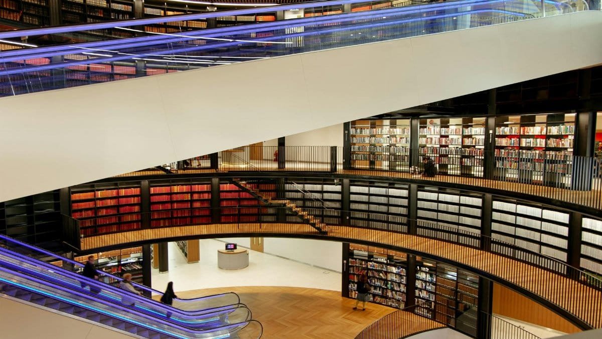 A spacious library with bookshelves, escalators, and modern design elements.