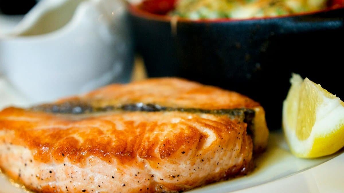 Delicious pan-seared salmon steak garnished with a lemon slice, showcasing a perfect dining experience.