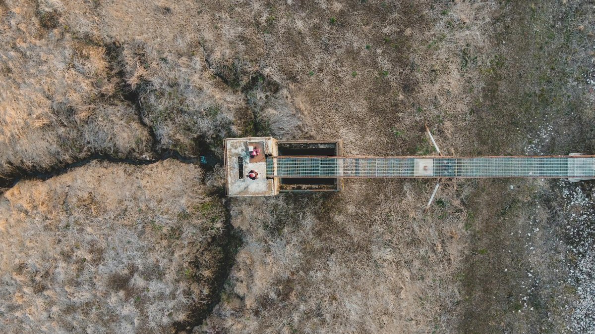 Aerial view of a solitary bridge spanning a barren landscape in Săcueni, Romania.