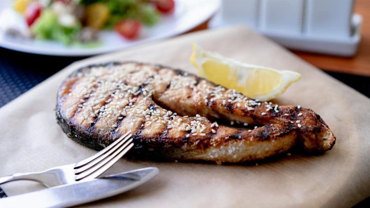 Delicious grilled salmon steak garnished with sesame seeds and lemon wedge, perfect for healthy eating.