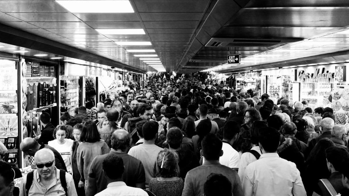 Bustling indoor market crowded with people of various ethnicities and ages.