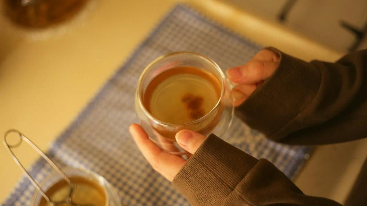A cozy scene of hands holding a warm glass of tea, perfect for autumn mornings.