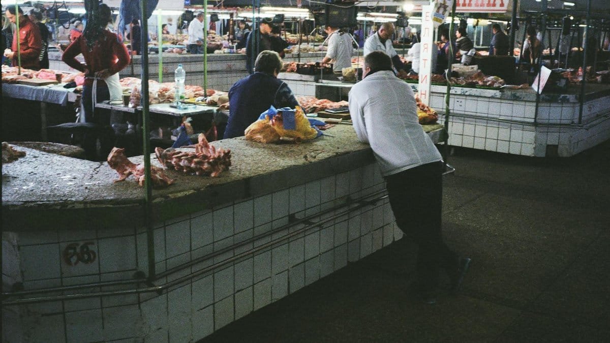 Vibrant scene of a busy wet market in Kyiv with people selling fresh meat and produce.