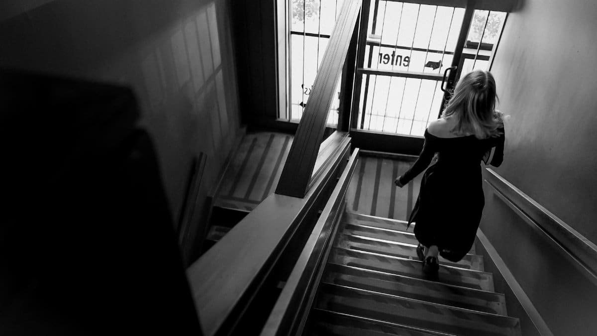 A woman descending a staircase in a black and white urban setting, elegant and mysterious.