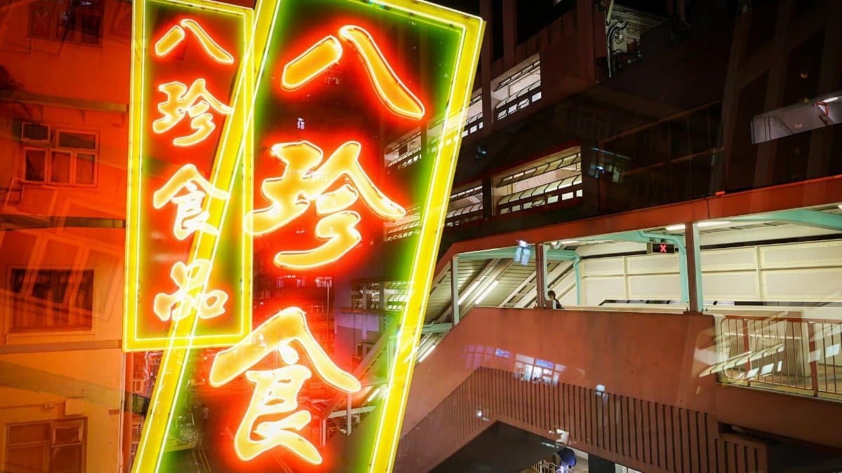 Colorful neon signs illuminate a bustling Hong Kong street at night, reflecting local urban culture.
