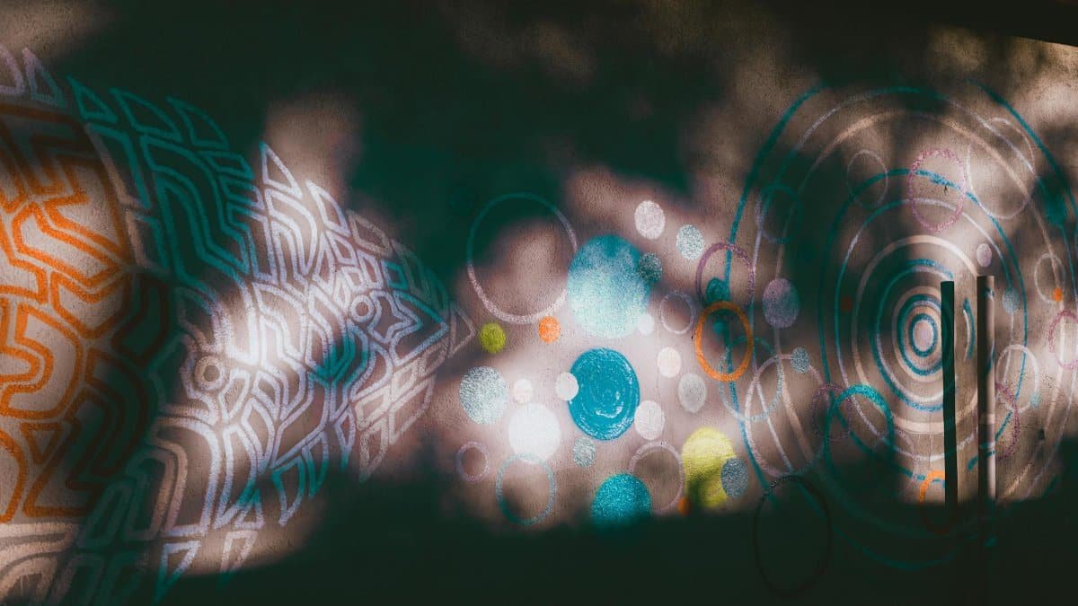 Vibrant graffiti with abstract shapes and patterns on a sunlit urban wall.