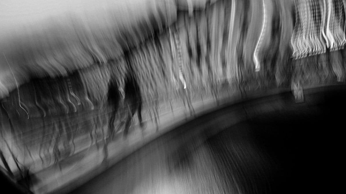 Black and white abstract photo showing blurred city motion near a waterway.