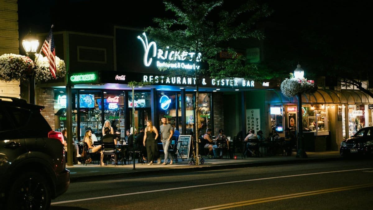 A bustling urban nightlife scene at a restaurant and oyster bar, with people dining outside.