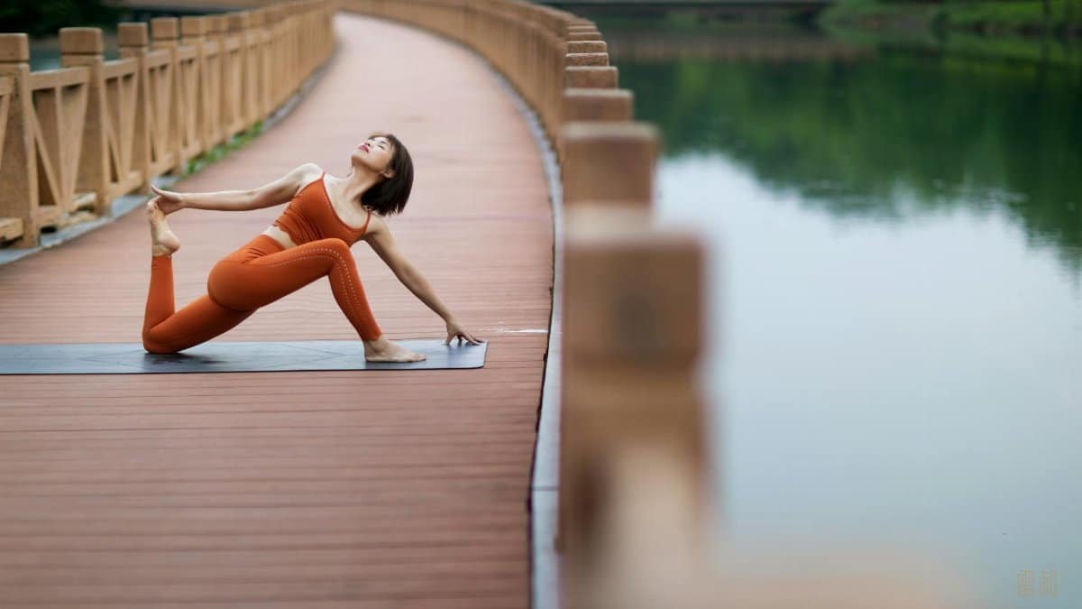 Woman doing yoga on a bridge, showcasing flexibility and mindfulness in a serene outdoor setting.