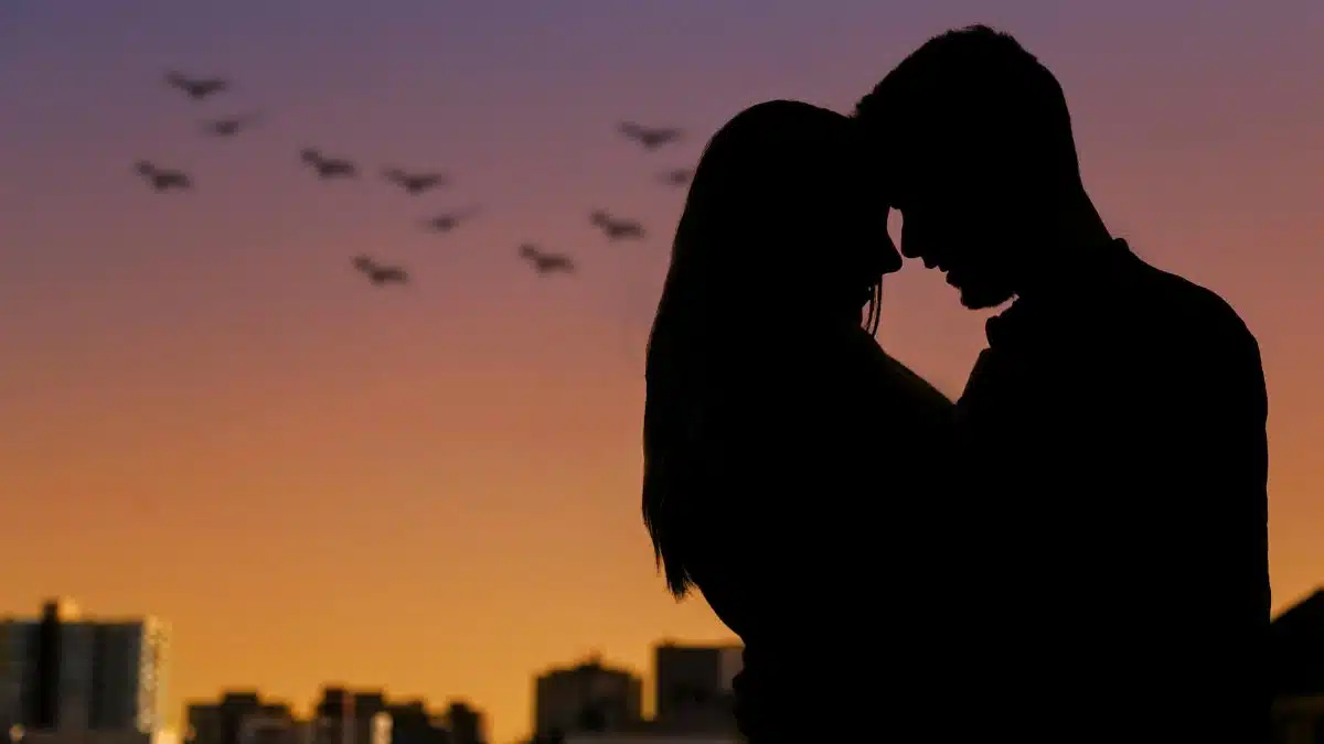 Silhouette of a couple embracing at sunset in an urban setting, evoking romance.