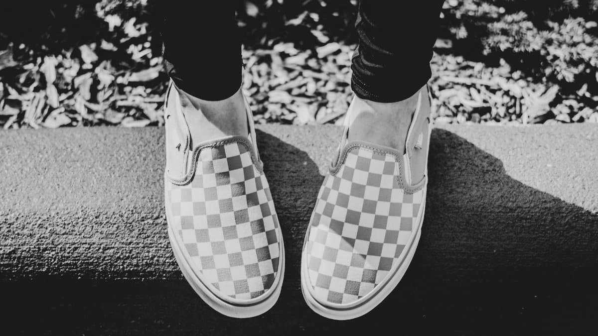 Black and white photo of checkered slip-on sneakers on a curb, fashion statement in Asheville.