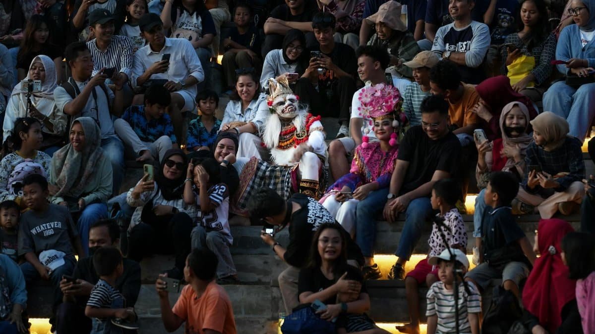 A mesmerizing traditional Balinese dance performance was witnessed by a large audience. Performers in traditional Balinese costumes and masks, such as the visible white masks, perform typi...