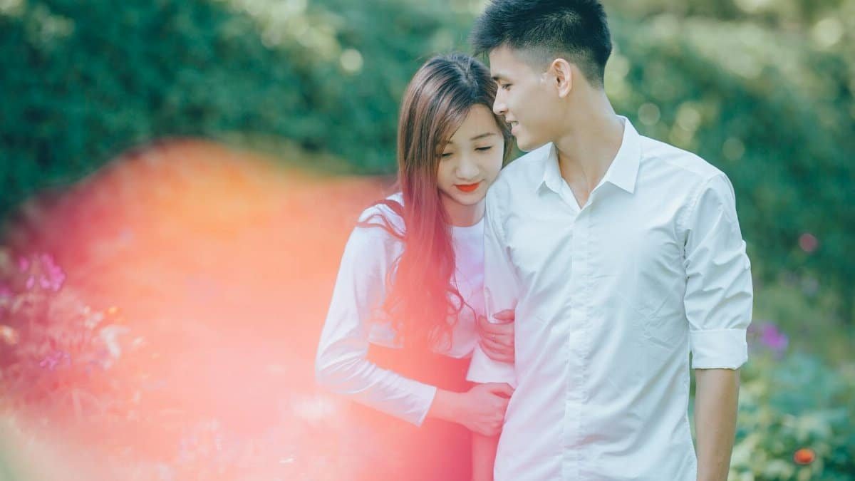 An affectionate couple enjoying a tender moment surrounded by lush greenery and flowers.