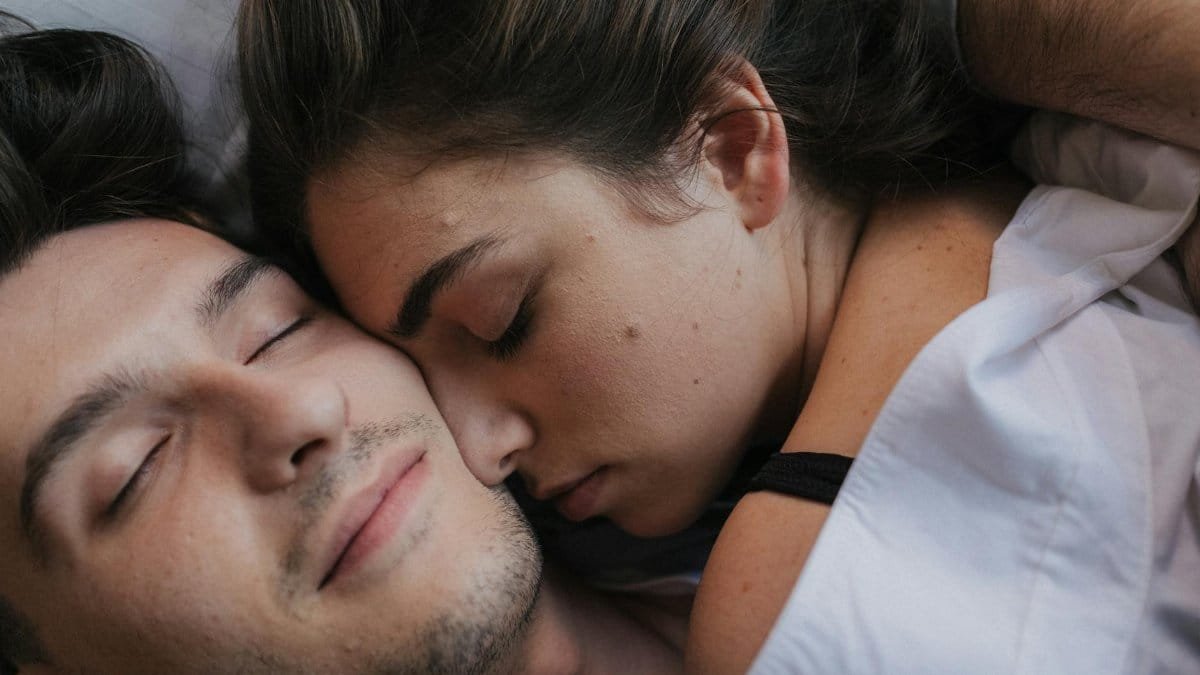 A close-up of an intimate couple cuddling and resting together in bed.