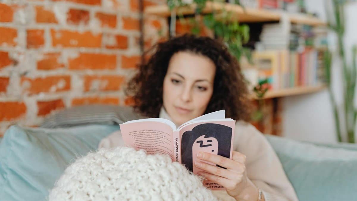 Woman enjoying a leisure reading moment at home on a cozy sofa.