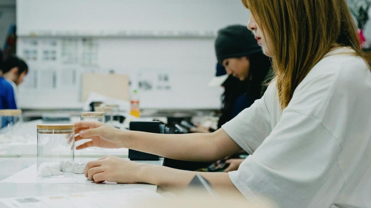 A group of art students in Tokyo focus on a creative workshop, working with drawing materials.