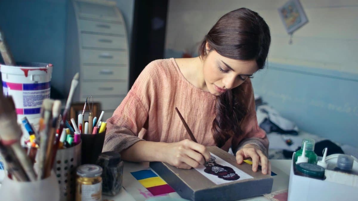 Female artist deeply engaged in painting at her creative studio workspace.