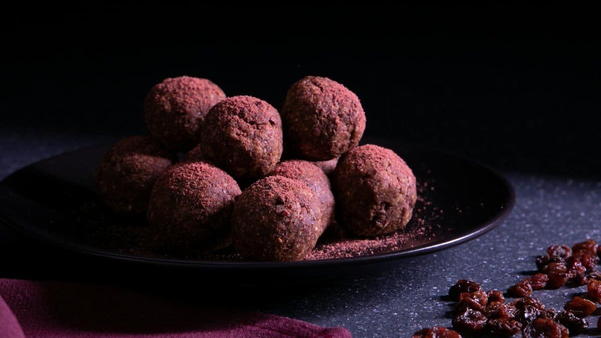 A mouth-watering display of chocolate truffles on a dark plate with scattered raisins.