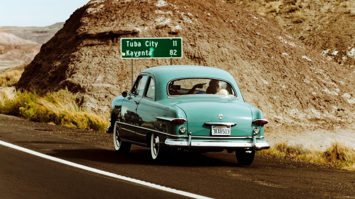 Classic vintage car driving through the scenic desert landscape of Arizona near Tuba City.