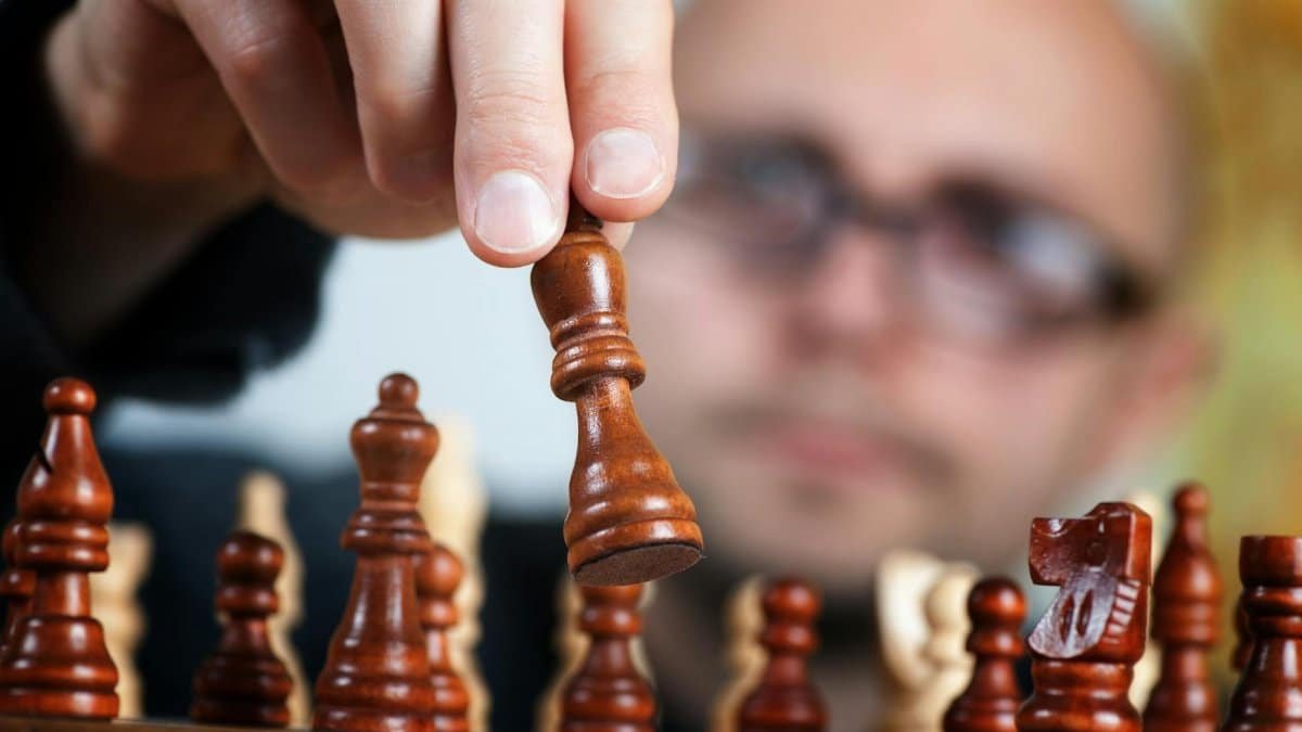 Close-up of a chess player making a strategic move with a focus on the chess piece and the player's intent.