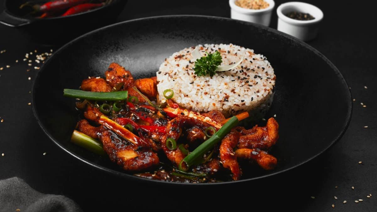 Delicious spicy stir-fried chicken paired with sesame rice, perfect for an indulgent meal.
