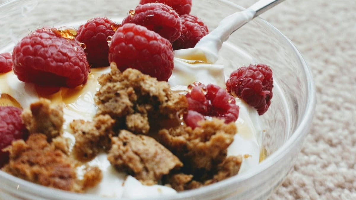 Close-up of a breakfast bowl with yogurt, fresh raspberries, and granola.