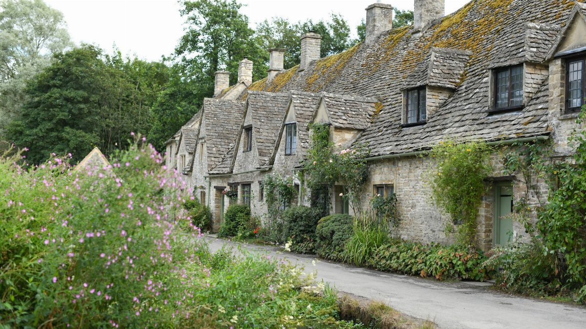 Idyllic stone cottages with lush gardens in a quaint English village.