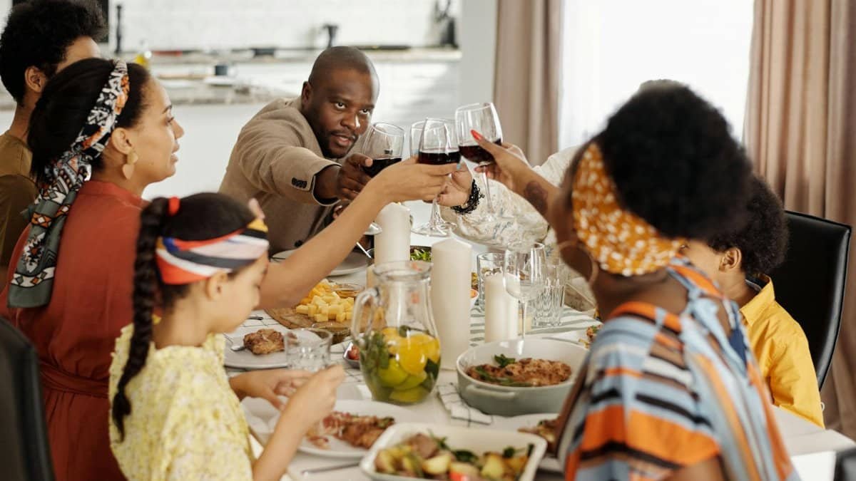 Family gathering in a cozy home, sharing a meal and raising glasses for a toast.