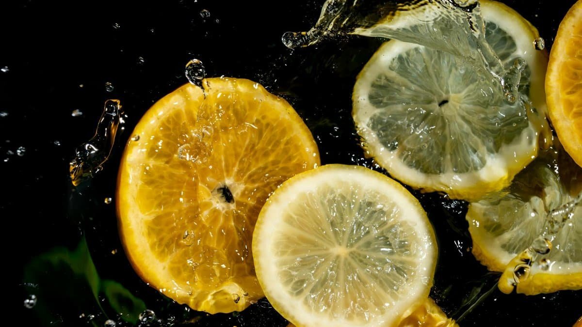 Vibrant lemon and orange slices splashing in water, capturing freshness.