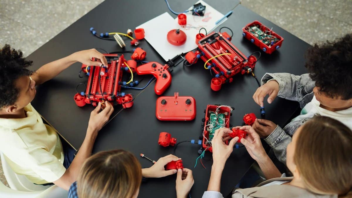 Group of children learning electronics and robotics with toys on a table, engaging in hands-on activities.