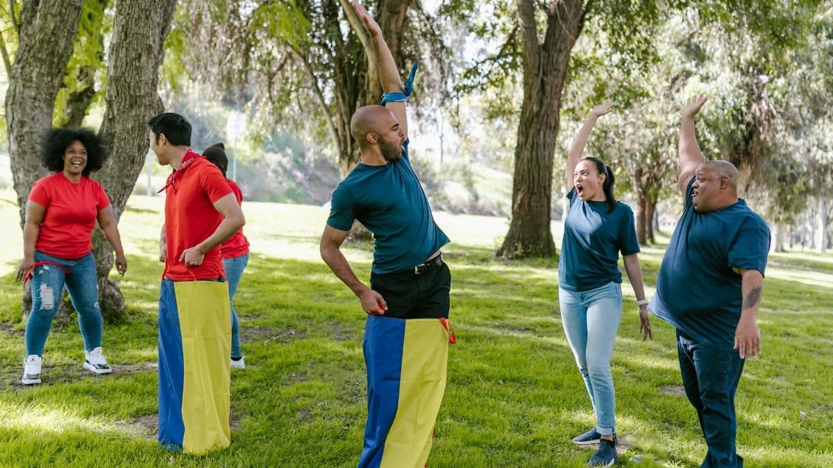 Group of adults enjoying team building games with cheer in a green park.