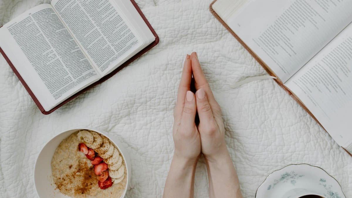 A serene morning scene with a person praying, an open Bible, oatmeal, and coffee.
