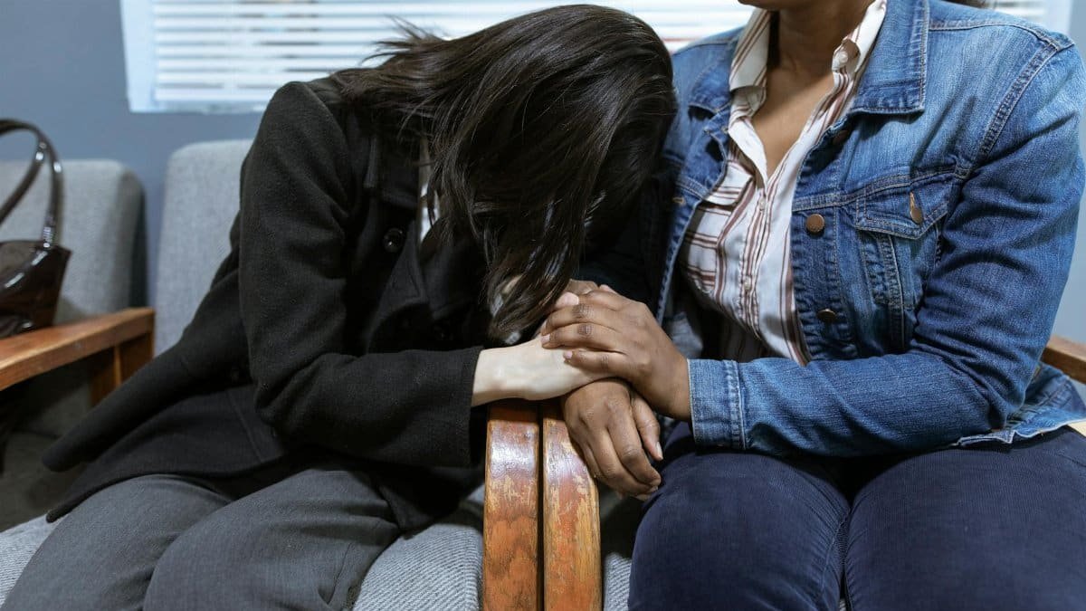 Two women offering emotional support, demonstrating compassion in a hospital setting.