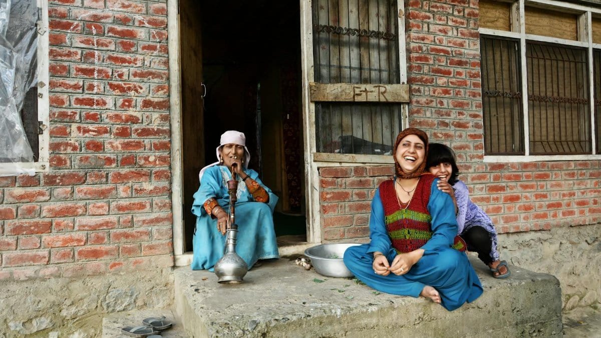 Smiling family sitting outside a rural brick house, reflecting happy moments and cultural heritage.