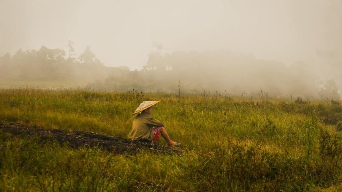 A farmer sits peacefully in a foggy meadow, capturing the essence of rural life in Meghalaya, India.