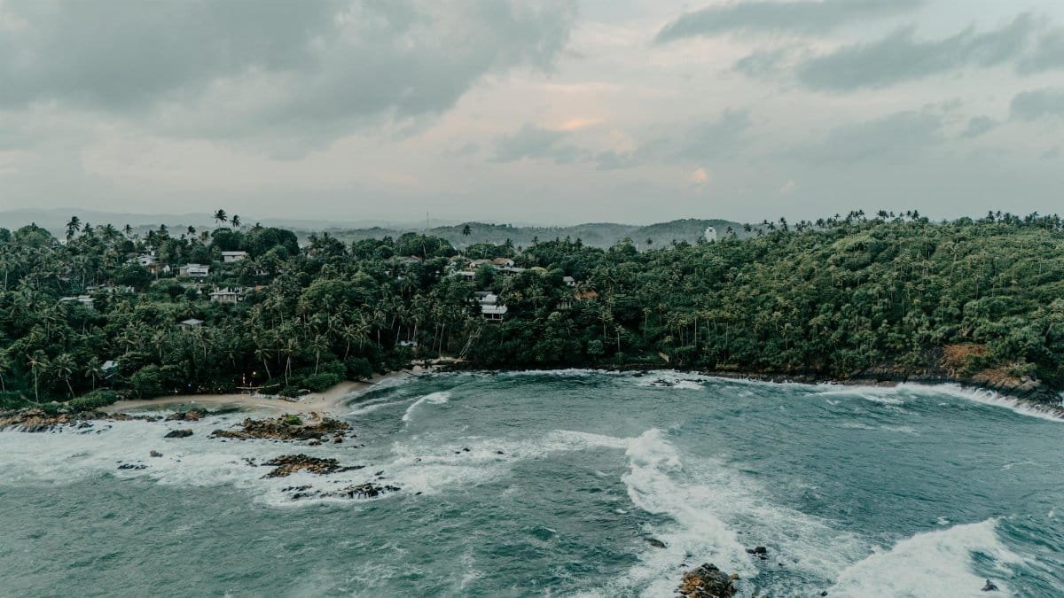 A breathtaking aerial view of the lush Sri Lankan coastline with waves crashing on the shore.