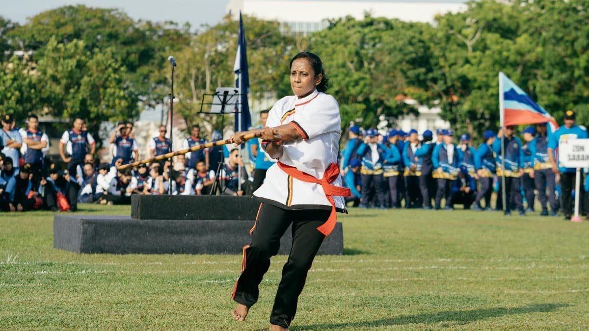 Woman performing Silambattam outdoors in George Town, Malaysia. Cultural martial arts display.