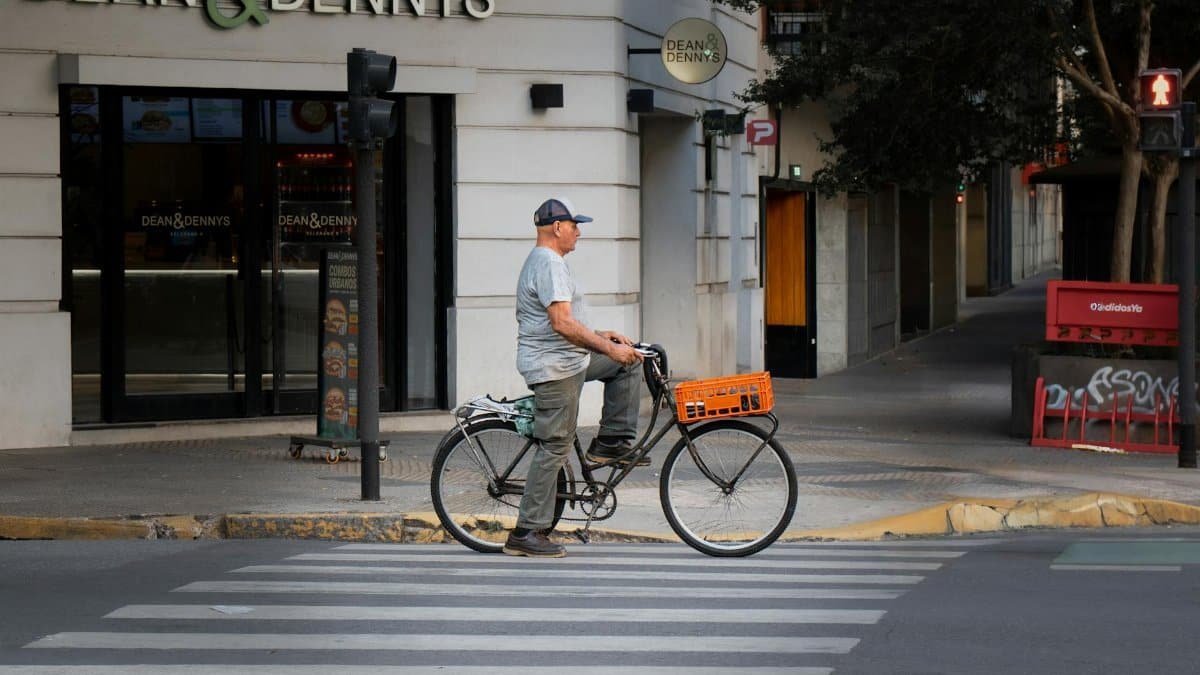 A man rides a bicycle past Dean & Dennys café on a quiet urban street.