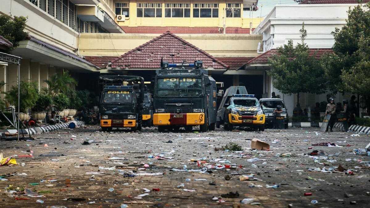 Police vehicles parked in an urban area surrounded by litter and debris.
