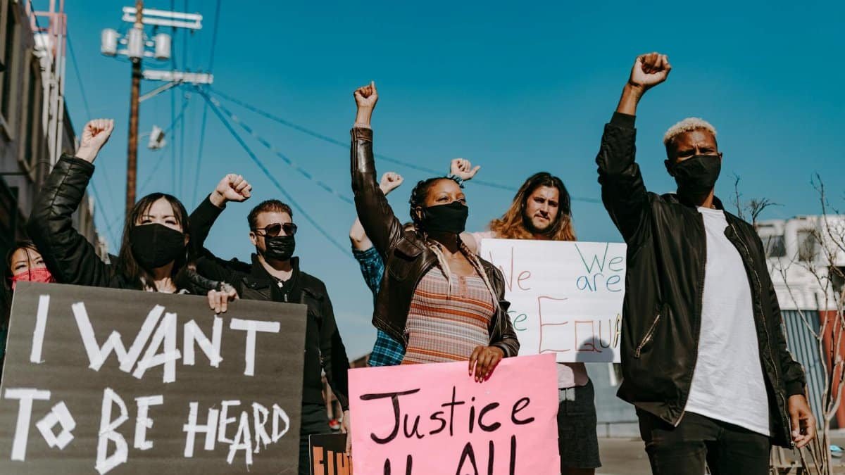 A diverse group of people protesting for justice and equality with banners.