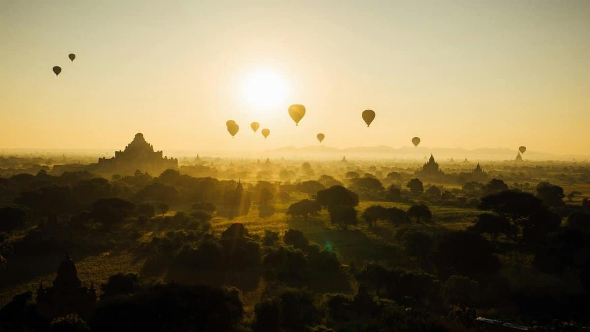Hot air balloons floating over Bagan temples at sunrise, creating a stunning silhouette against the golden sky.