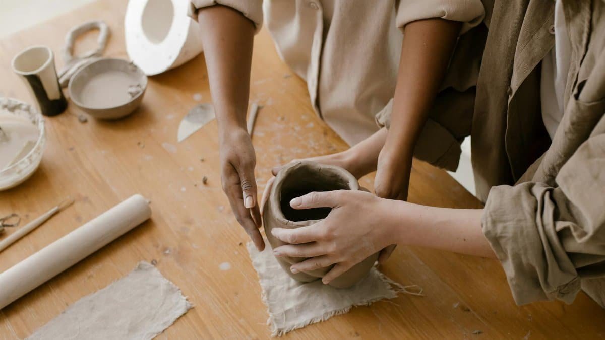 Close-up of hands crafting a pottery vase in an art studio setting.