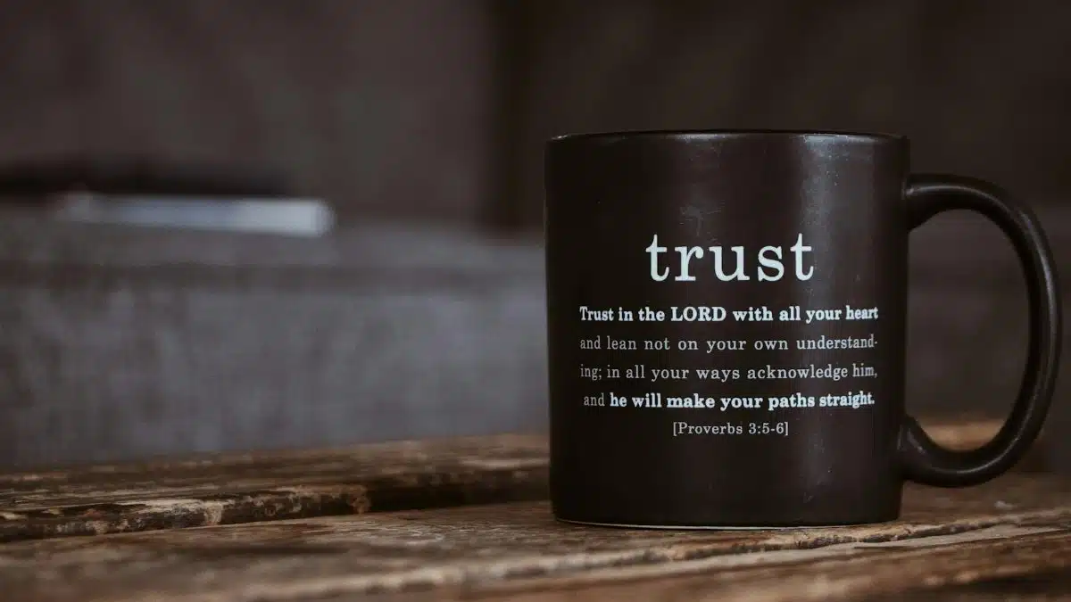 A rustic black mug with an inspirational religious quote from the Bible on a wooden table.