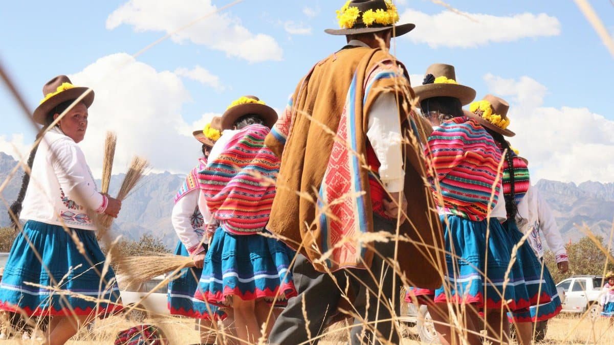 Andean people in colorful attire participating in a traditional dance outdoors.