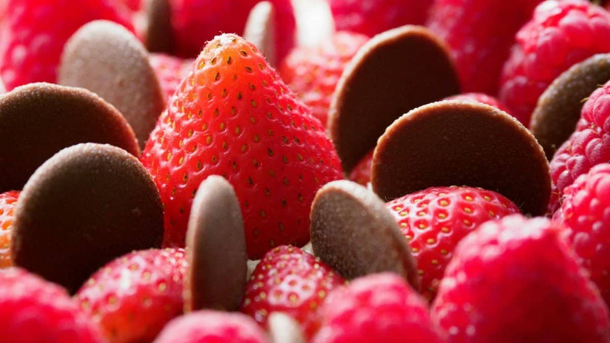 Fresh strawberries, raspberries, and dark chocolate chips in a close-up view, perfect for dessert lovers.
