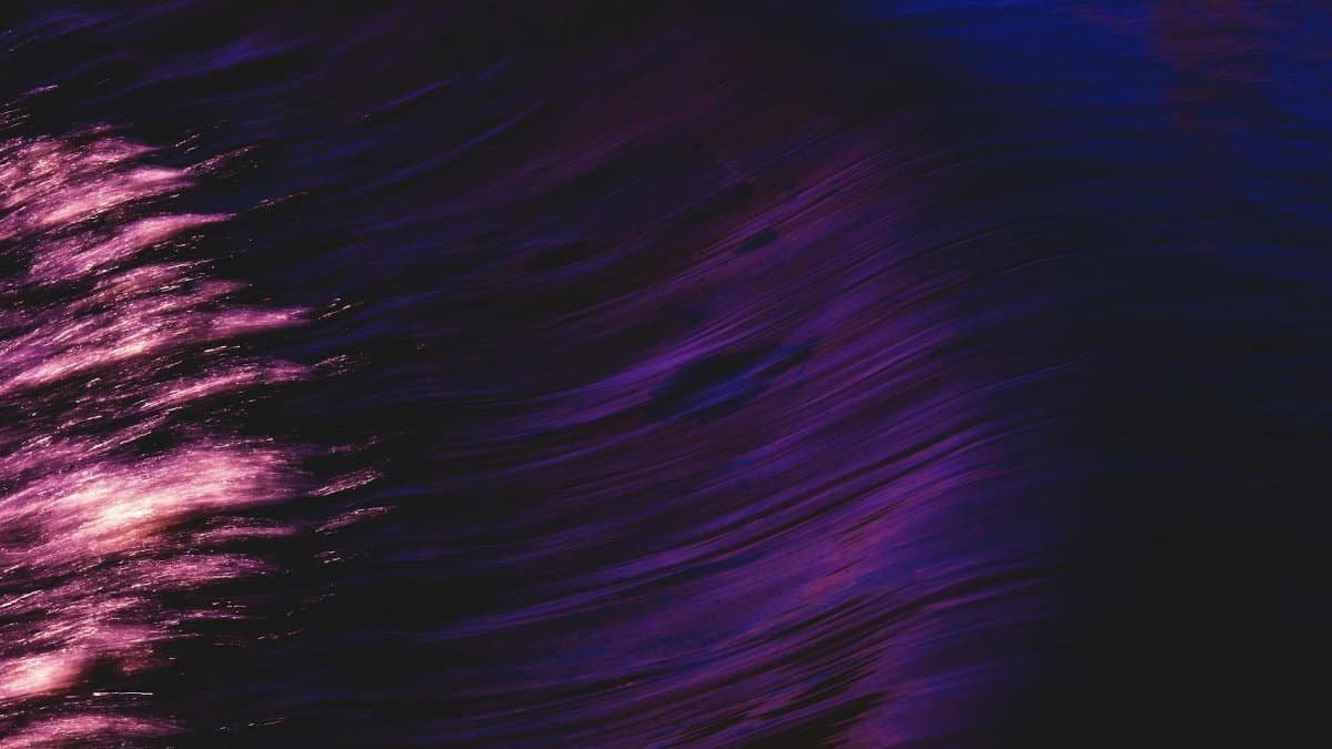 Swirling abstract art with vibrant purple and pink reflections in water, evoking a sense of motion and flow.