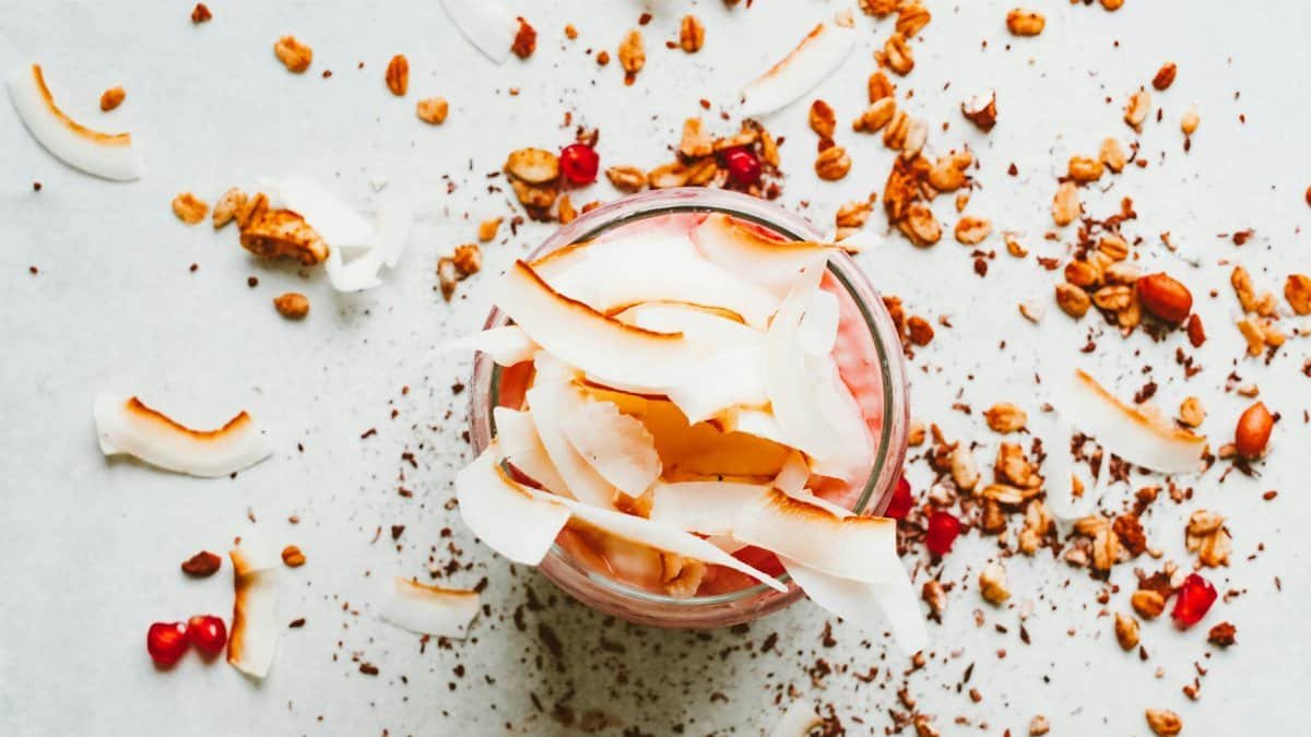 Delicious yogurt parfait topped with coconut flakes, granola, and pomegranate seeds.